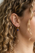 Ohrringe Sarah – Model mit lockigem Haar trägt vergoldete Creole mit blauem Lapislazuli