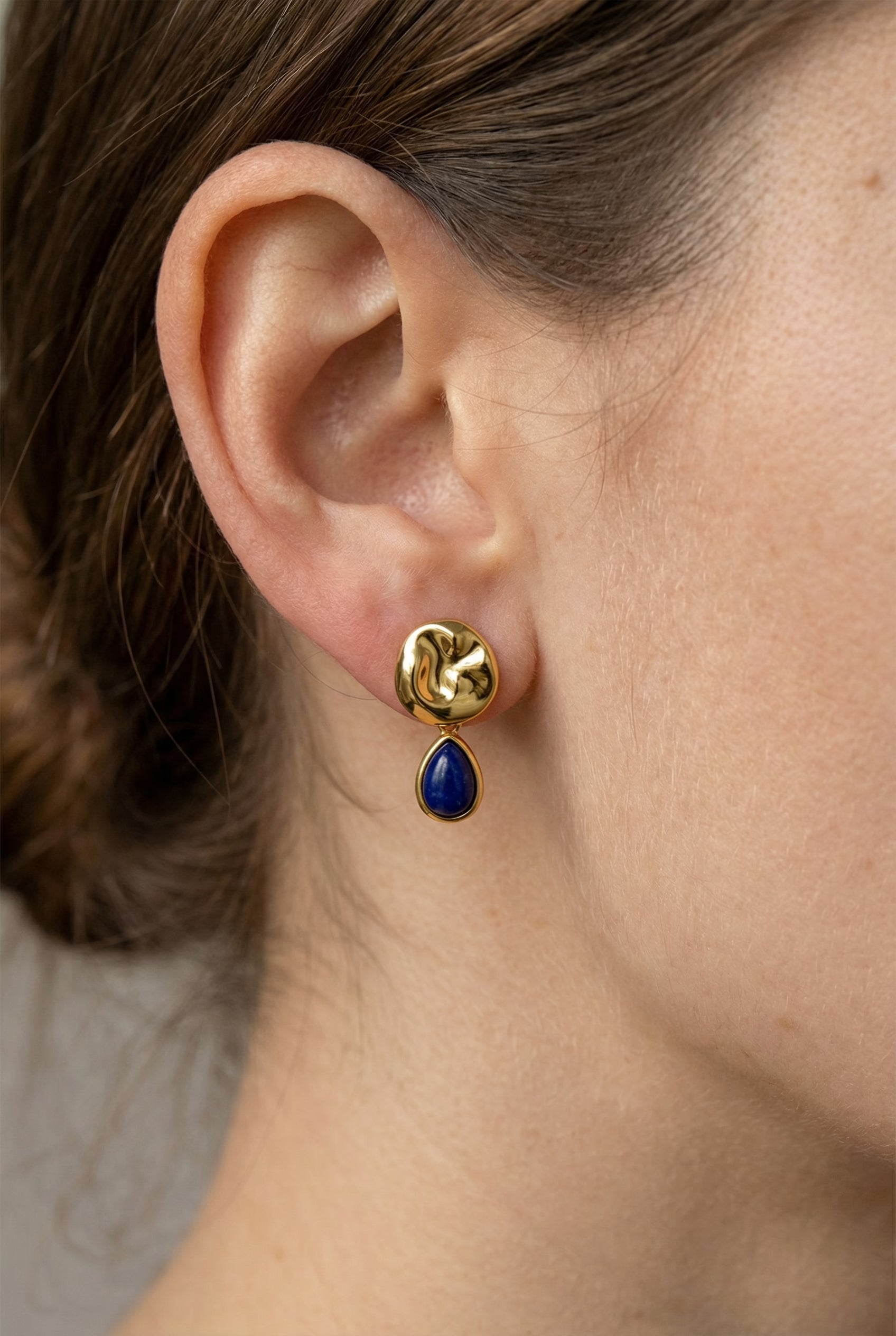 Ohrringe Anne – Model trägt vergoldete Ohrringe mit blauem Lapislazuli-Tropfen